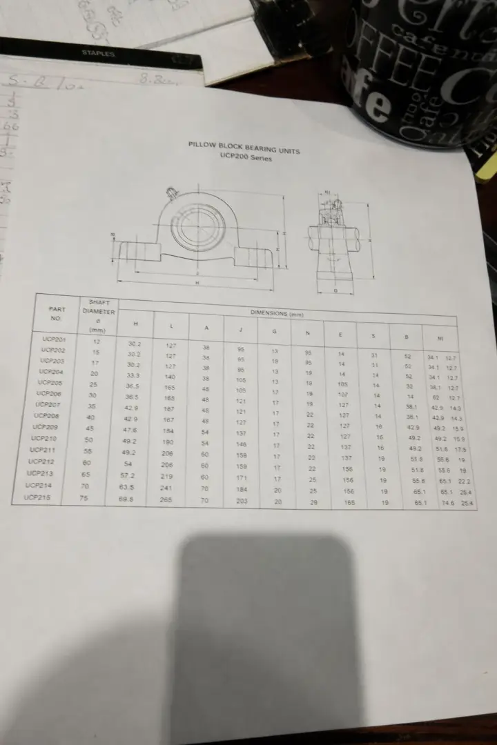 A printed bearing datasheet page on a desk, showing a drawing and a table of dimensions