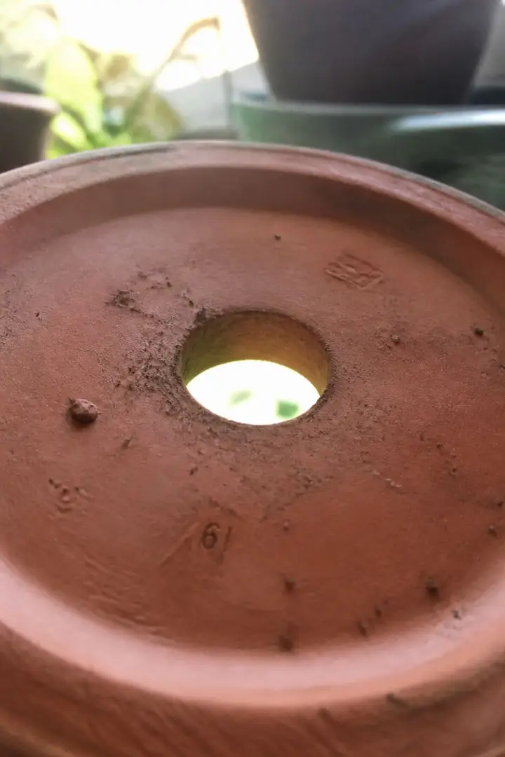 An upturned terracotta plant pot showing the oversized hole in its base